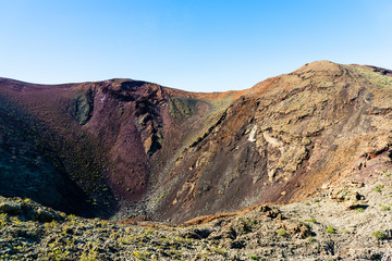 Timanfaya National Park, mountains of fire at Lanzarote, Canary Islands, Spain. Unique panoramic view of spectacular corrosioned lava ground layers s of a huge volcano cone.