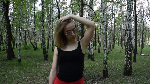 Young girl in t-shirt and red skirt shoots with gun in forest.
