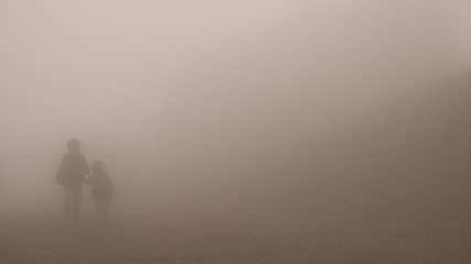 mom and son walk hand in hand in the mountain mist