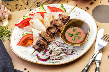 pork kebabs on a plate with sauce on a wooden table