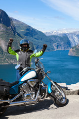 Exited woman motorcyclist glads to travel by motorcycle in Norway, Scandinavia. Viewpoint with Northern sea and fjords