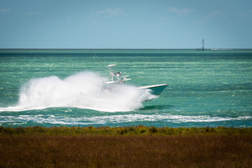 Fishing charter boat flying through the waves with a large bow splash outside of Key West harbor in...