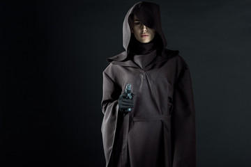 serious woman in death costume aiming gun at camera on black