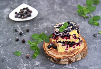 Sweet sliced cake with cornmeal and black currant. Decorated with fresh mint, powdered sugar and berries of frozen black currant.
