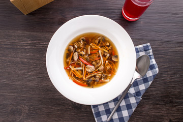 Clear soup with beef and noodles and berry drink on wooden table