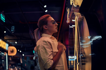 Portrait of pensive trendy woman in neon lights with darkness around.