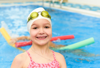 Happy little girl swimming in the pool. Caucasian child is playing fun in the kindergarten pool.