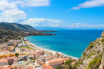 Paraglider flying above the amazing landscape of coastal city Cefalu in beautiful Sicily....