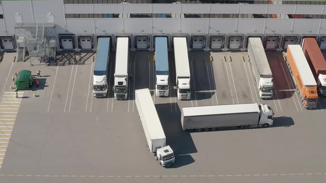 Aerial shot of truck drives up at warehouse for loading or unloading. Logistics, distribution center.