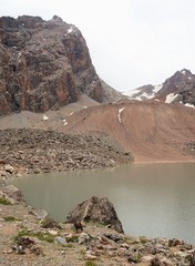 View of Mountain lake, lake Mutnoe and a donkey standing next to a large rock, Fann mountains, Tajikistan 
