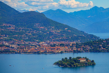 Fototapeta na wymiar AERIAL: Scenic view of a coastal town and islet in a beautiful Italian lake.