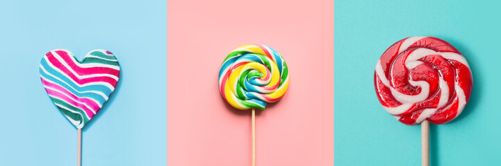 Three colorful lollipops candy as heart and swirl on blue and pink. Funny concept. Top view....