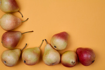 Ripe juicy pears placed on orange background. Colorful fruit pattern or background.