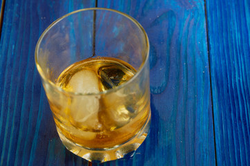 A glass of strong alcohol with ice in a transparent glass