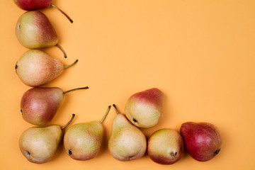 Ripe juicy pears placed on orange background. Colorful fruit pattern or background.