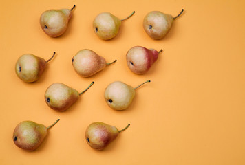 Pears placed as pattern on orange background. Colorful fruit pattern or background