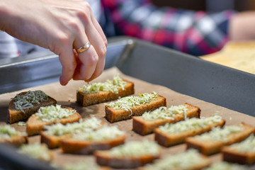 Black bread with cheese and seasonings, the girl sprinkles sliced bread.