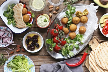 Middle eastern, arabic or mediterranean appetizers table concept with falafel, pita flatbread, bulgur and tomato salads, grilled vegetables, stuffed grape leaves,olives and nuts.
