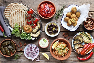 Middle eastern, arabic or mediterranean appetizers table concept with falafel, pita flatbread, bulgur and tomato salads, grilled vegetables, stuffed grape leaves,olives and nuts.
