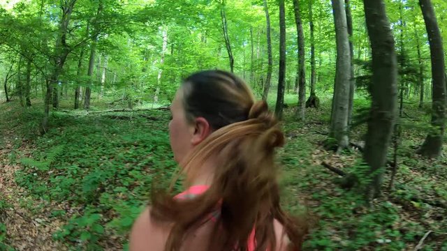 Side tracking shot of a woman running in the forest