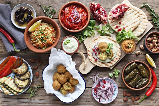 Middle Eastern, Arabic Or Mediterranean Appetizers Table Concept With Falafel, Pita Flatbread, Bulgur And Tomato Salads, Grilled Vegetables, Stuffed Grape Leaves,olives And Nuts.