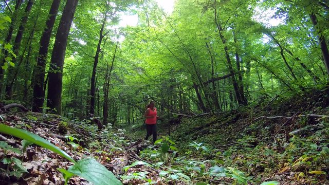 Overweight woman running  up a forest path