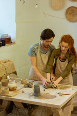 Bearded focused teacher explaining his student basics of pottery