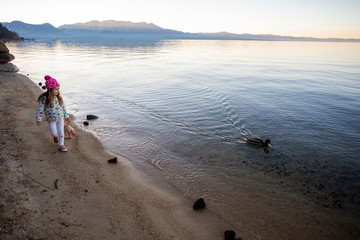 A young girl walking alone near the shore of Lake Tahoe at sunset. 