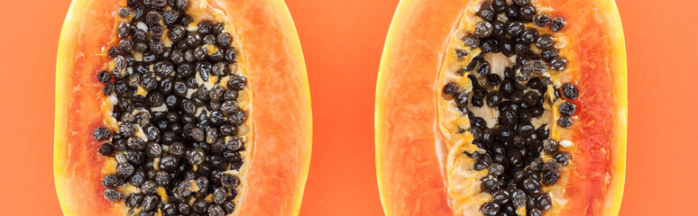 panoramic shot of papaya halves with black seeds isolated on orange