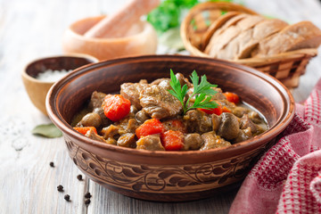 Turkey meat stew with mushrooms and vegetables in ceramic bowl on wooden table. Selective focus.