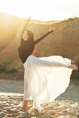 Naklejka premium Ballet woman Dancer at Sunset beach. Classical dance in white chiffon skirt