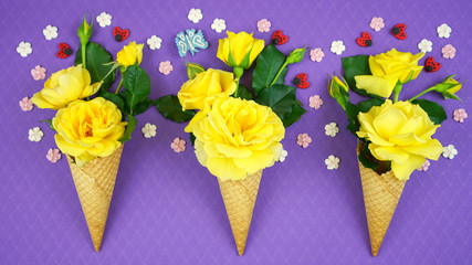 Summertime flatlay concept with ice cream cones filled with fruit, flowers and candy.