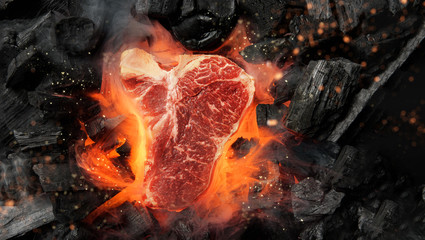raw marbled beef steak with coals and smoke