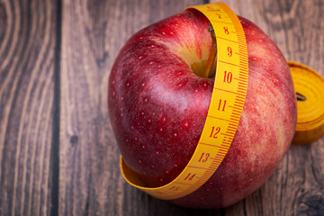 Red Apple and Soft Vinyl Measuring Tape on wooden background.