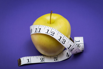 Yellow Apple and Soft Vinyl Measuring Tape on purple background.