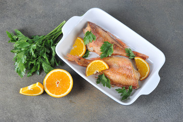 Baked Sebastes  with oranges. Gray background. View from above.  