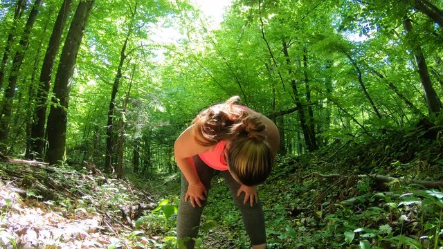 TS Overweight woman running up a forest path and stopping to catch her breath