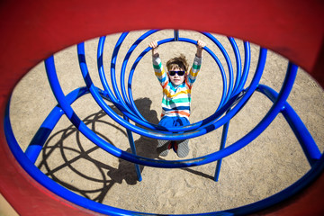 Cute young child boy or kid playing in tunnel on playground