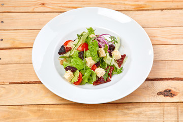 vegetarian salad with dried tomatoes and croutons on the wooden background