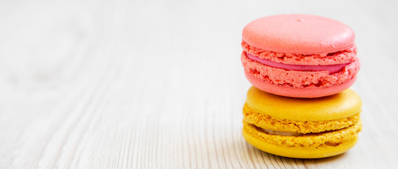 Colorful macaroons on a white wooden background, side view. Space for text.