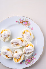 Sliced boiled eggs with mayonnaise and pepper in white plate isolated top view