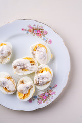 Sliced boiled eggs with mayonnaise and pepper in white plate isolated top view