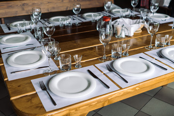 Glasses, forks, knives, plates on a table in restaurant served for dinner.