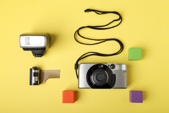 Macchina fotografica e accessori su un piano di colore giallo