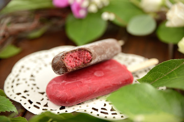fruit ice cream on a stick, on a background of green leaves