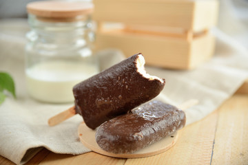 vanilla ice cream in chocolate coating, on a wooden table