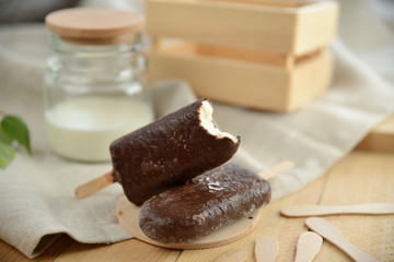 vanilla ice cream in chocolate coating, on a wooden table