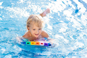 Fototapeta na wymiar Child learning to swim. Kids in swimming pool.