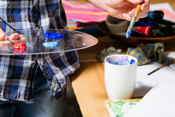 Artist at work. Paints on palette paintbrush in hand. Focus on creative idea. Artwork in process. Hobby therapy occupation.