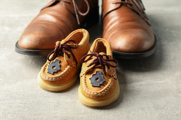 Brown leather shoes and children's shoes on grey background, space for text and closeup